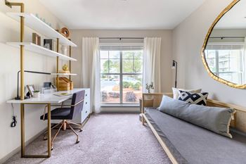 A bedroom with a bed and a desk and a window